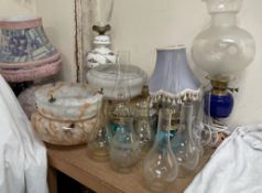 An oil lamp with a blue glass reservoir, together with other oil lamps, glass lamp shades,