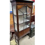 An Edwardian mahogany display cabinet with a moulded cornice above a glazed door and sides on