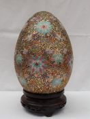 A Cloisonne enamel egg, decorated with flower heads and scrolls,