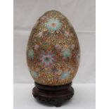 A Cloisonne enamel egg, decorated with flower heads and scrolls,