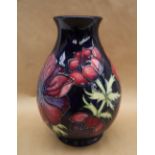 A Moorcroft pottery vase decorated in the Clematis pattern to a royal blue ground,