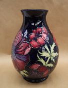 A Moorcroft pottery vase decorated in the Clematis pattern to a royal blue ground,