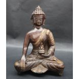A bronze seated Buddhistic figure, holding a lidded vase in its right hand, 23.