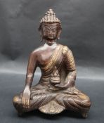 A bronze seated Buddhistic figure, holding a lidded vase in its right hand, 23.