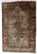 A Persian silk rug, with a red ground decorated with interlocking flowerheads and leaves,
