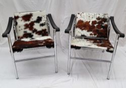 A pair of cow hide and chrome elbow chairs after Le Corbusier LCI,