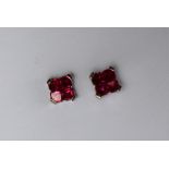 A pair of ruby earrings, each set with four princess cut rubies to a white metal setting and post,