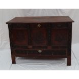 An oak coffer the rectangular moulded top above a carved three panel front and base drawer on