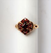 A 9ct yellow gold garnet cluster ring, set with a pointed central garnet and round faceted garnets,