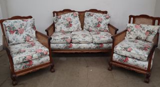 An early 20th century bergere suite, comprising a tow seater settee and two arm chairs,