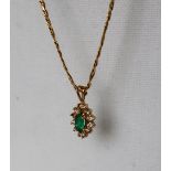 A 14ct yellow gold emerald and diamond pendant set with a pointed oval faceted emerald surrounded