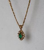 A 14ct yellow gold emerald and diamond pendant set with a pointed oval faceted emerald surrounded