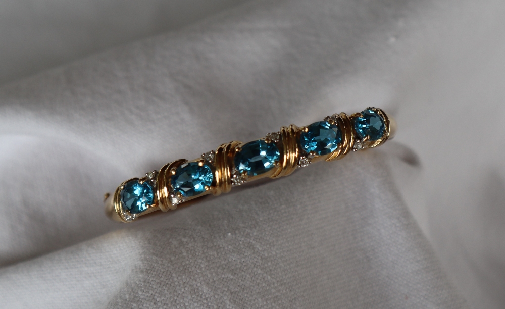 A 14ct yellow gold blue topaz and diamond set hinged bangle,