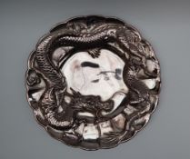 A Chinese white metal dish, with a raised dragon, to a multiple lobed circular body, 30.