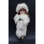 A bisque head "snow baby" doll, with fixed eyes and open mouth with teeth, dressed in fur,