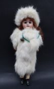 A bisque head "snow baby" doll, with fixed eyes and open mouth with teeth, dressed in fur,