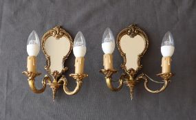 A pair of gilt metal twin branch wall lights with a mirrored panel back,