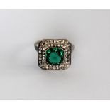 A dress ring set with diamonds and a princess cut green stone to a white metal setting and shank,