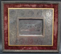 A white metal plaque decorated to the centre with a scene of the Last Supper,