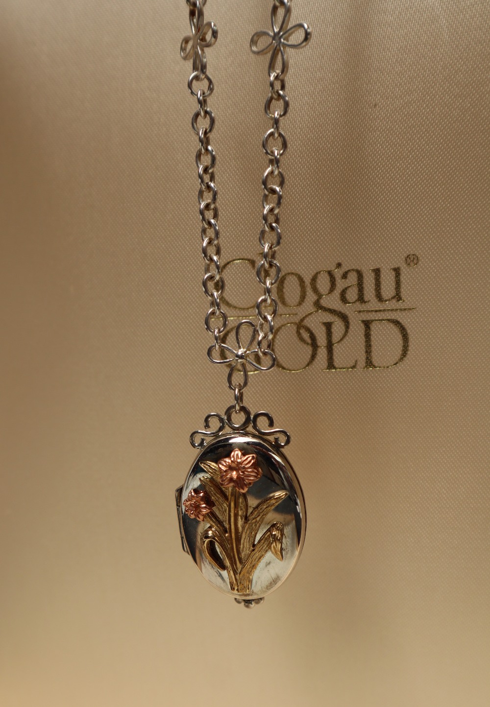 A Clogau silver locket with an applied gold daffodils on a silver necklace, approximately 17.