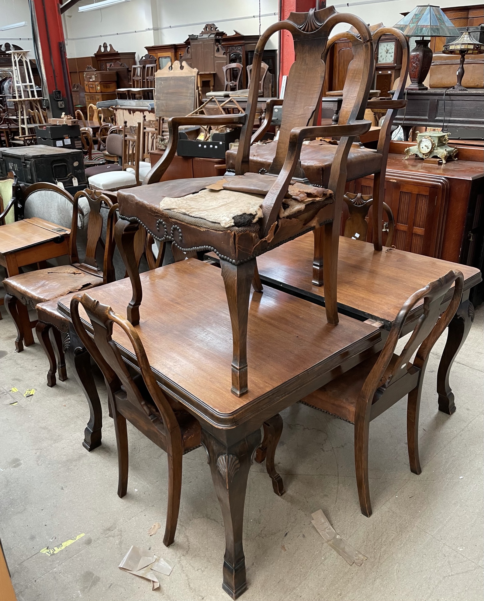 An Edwardian walnut extending dining table together with eight dining chairs with shell carved