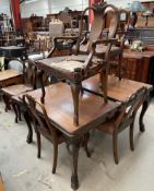 An Edwardian walnut extending dining table together with eight dining chairs with shell carved
