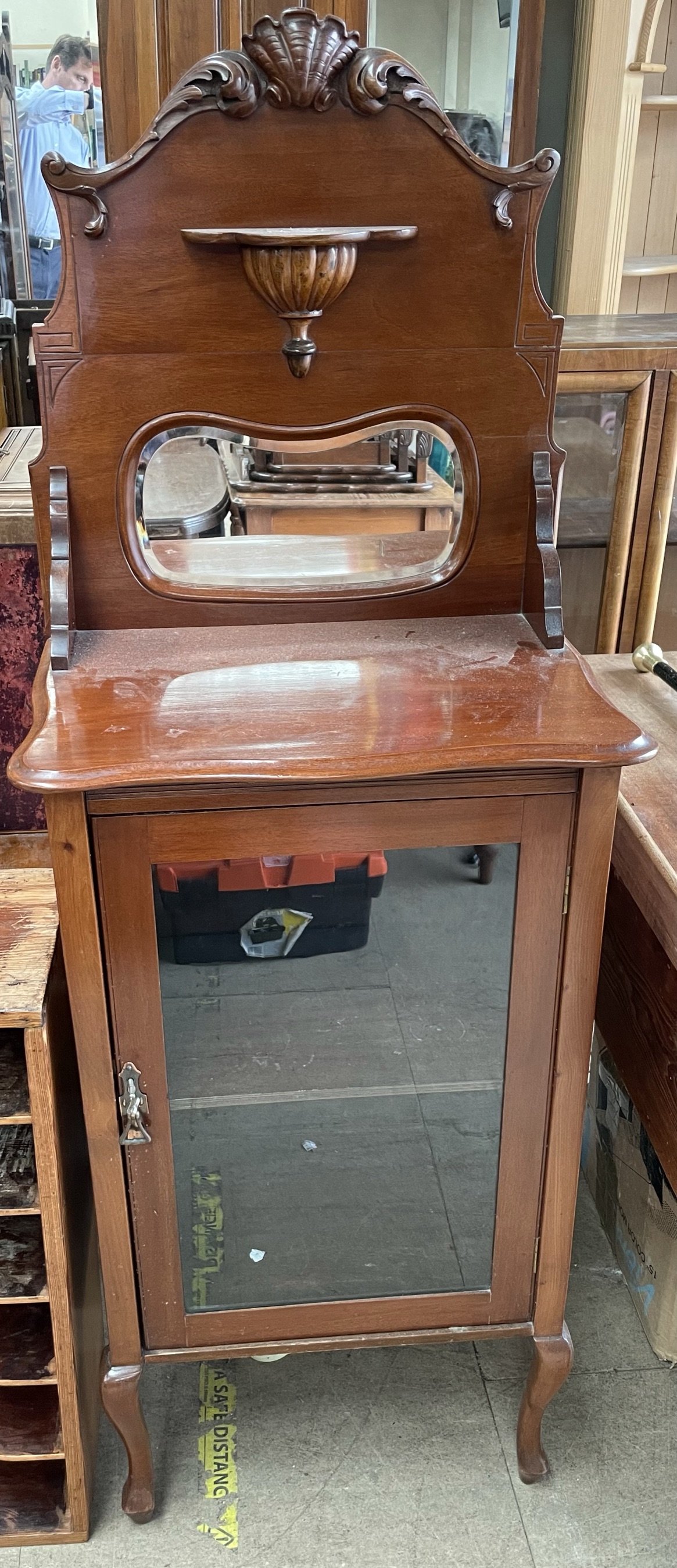 An Edwardian mahogany music cabinet with a shell carved mirror back,