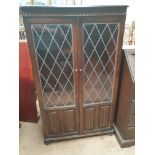 An oak bookcase with leaded glass doors and linen fold panels,