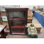 A bronze model of a seated buddha on a wooden base together with a wall mounted display cabinet