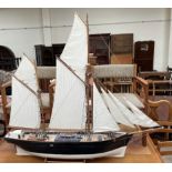 A model ship, with two masts and sails unfurled, on a stand,