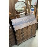 A reproduction mahogany bureau with a sloping fall and fitted interior above two short and three