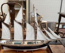 A model ship, with three masts and unfurled sails, bears a plaque for Jane Banks, Bideford,
