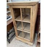 A pine side cabinet with a square top above a glazed door on bracket feet
