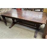 An oak refectory table of rectangular form with a carved frieze on cup and cover legs