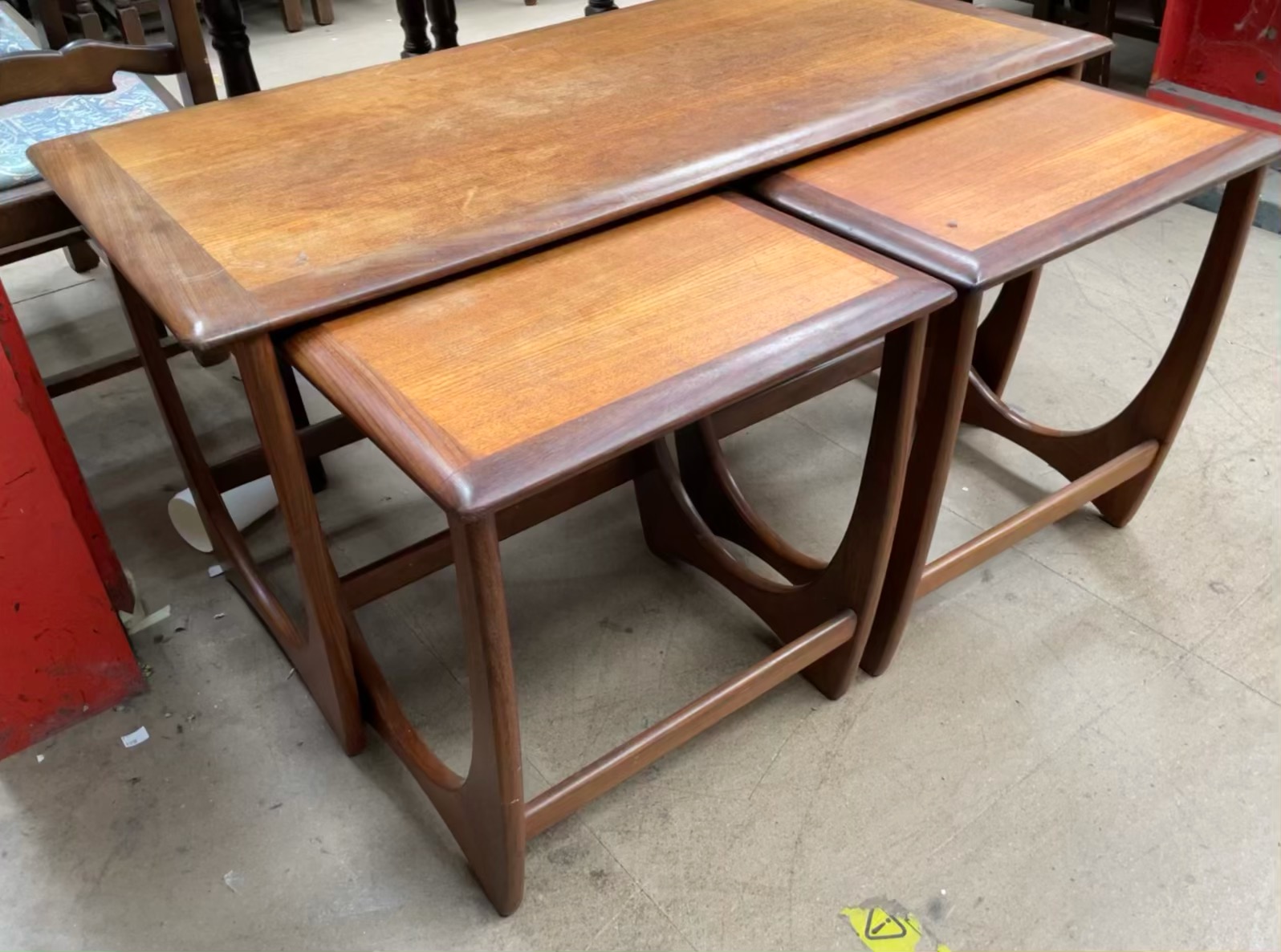 A mid 20th century teak nest of tables, with a crossbanded coffee table and two occasional tables,