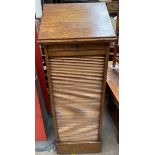 An oak tambour fronted filing cabinet, with a hinged, sloping top above a tambour front,