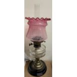 An oil lamp with clear glass reservoir and etched ruby glass shade