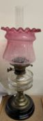 An oil lamp with clear glass reservoir and etched ruby glass shade