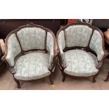 A pair of continental carved and upholstered tub chairs decorated with scrolling leaves,