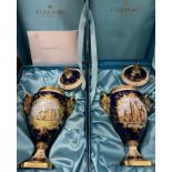 A pair of limited edition Coalport porcelain lidded rams head vases one painted with a view of