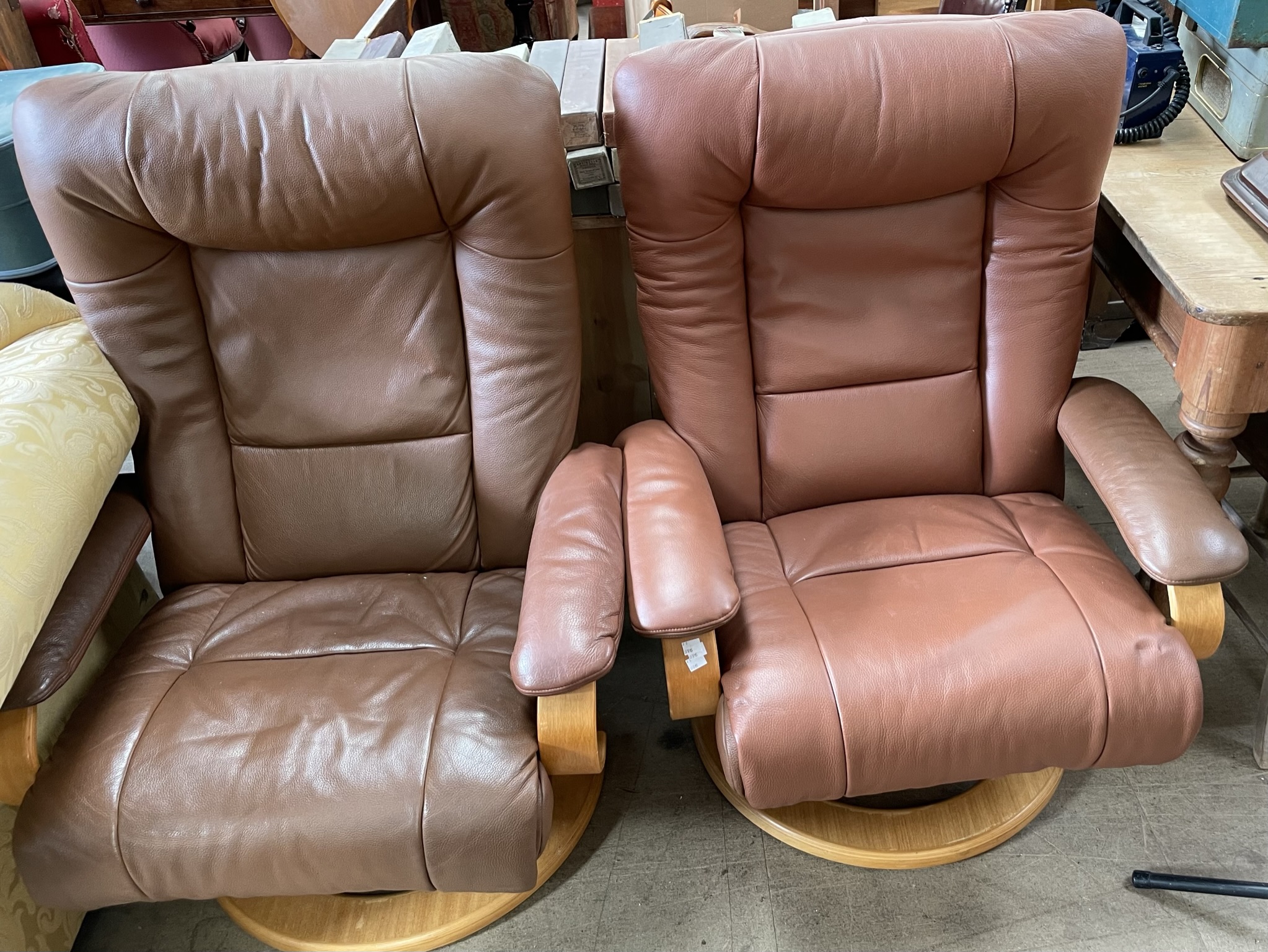 A pair of brown leather elbow chairs