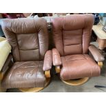 A pair of brown leather elbow chairs
