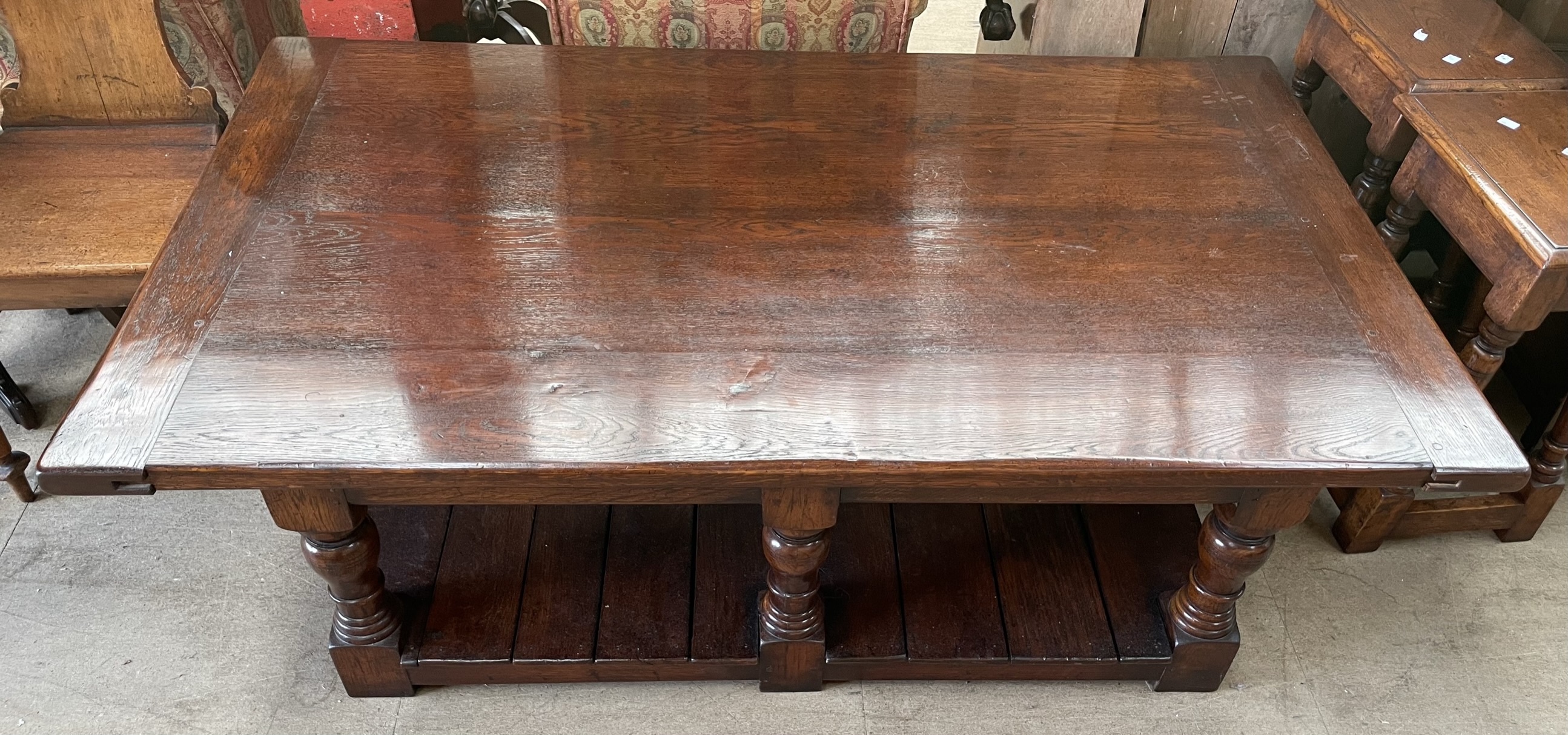 A large oak coffee table with a rectangular planked top on turned legs united by a planked