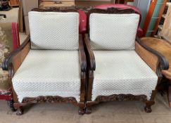 A pair of mahogany framed bergere single caned arm chairs with a carved front rail and claw and