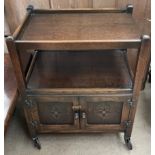 A 20th century oak tea trolley with a rectangular top above a pair of cupboards on wheels