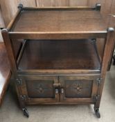 A 20th century oak tea trolley with a rectangular top above a pair of cupboards on wheels