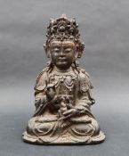 A bronze Buddhistic seated figure, with right hand raised, left hand holding a flame,