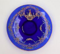 A blue glass saucer dish, painted with a maiden in a flowing dress with fan to a swag border,