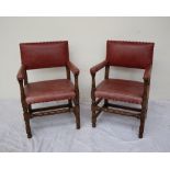 A pair of red leather upholstered and oak elbow chairs,