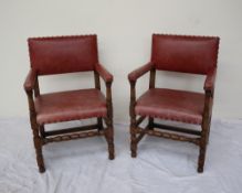 A pair of red leather upholstered and oak elbow chairs,